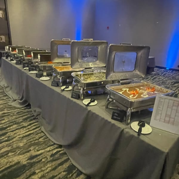 A long buffet table with multiple chafing dishes filled with various Indian dishes.